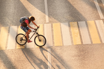 Naklejka premium young man riding a bicycle across the road on a pedestrian crossing