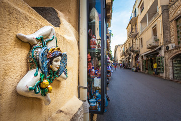 TAORMINA, ITALY - OCTOBER 16, 2014: Typical Sicilian Souvenir in ceramic symbolising the sunshine and triskelions - symbol of Sicily - obrazy, fototapety, plakaty