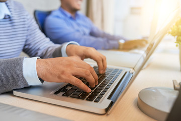 Faceless view of casual workers using laptops at desk in modern light office