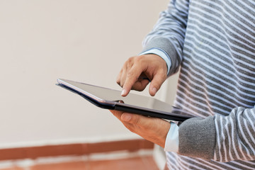 Faceless shot of casual man in office using tablet tapping on touchscreen