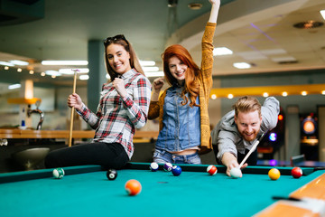 Fototapeta premium Happy friends enjoying playing pool