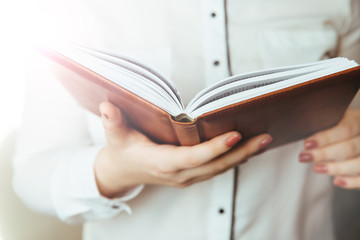 woman in white shirt keeping brown book in hands