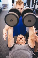  Senior man lifting weights assisted by gym instructor © Photocreo Bednarek