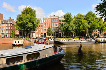 Kanał w Amsterdamie, barka, zabytkowe kamienice i zielone drzewa. © W Korczewski
