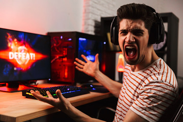 Side view of Angry gamer playing video games on computer