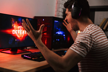 Side view of displeased gamer playing video games on computer