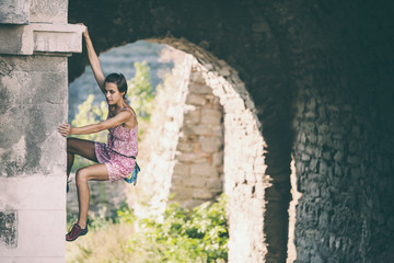 Fototapeta na wymiar The girl climbs the stone wall.