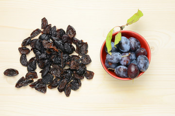 Fresh and dried plums with leaves on a wooden table background, Flat lay composition.