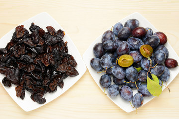 Fresh and dried plums with leaves on a wooden table background, Flat lay composition.