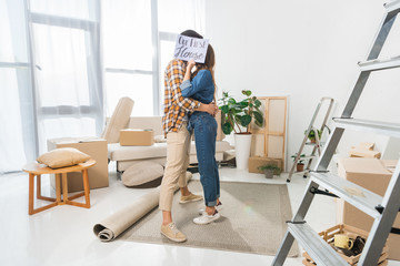 obscured view of couple kissing behind our first house card at new home