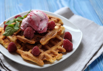 Plate of belgian waffles with ice cream and fresh berries over blue wooden background, top view