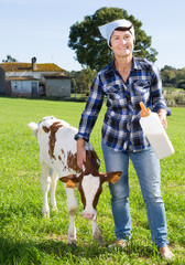 woman feeds two week old calf from bottle with dummy at lawn