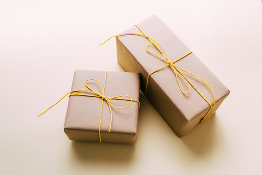 Gift boxes wrapped in brown kraft paper and tied with twine with beads lie on a yellow background. Gift delivery.Close-up.Design postcards for the holidays. Place for text