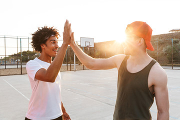 Two young cheerful multiethnic men basketball players