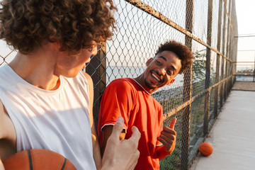 Two young smiling multiethnic men basketball players