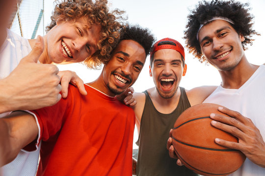 Photo closeup of muscular sporty men smiling and taking selfie, while playing basketball at playground outdoor during summer sunny day