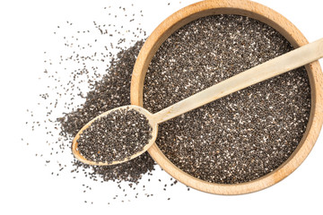 Chia seeds in wooden spoon on top of a wooden bowl with some spread on the blurred white background