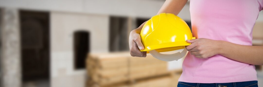 Composite image of woman holding hard hat against grey