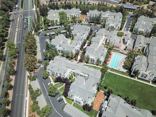 Aerial view typical multi-level apartment homes with swimming pool near freeway in Silicon Valley,...
