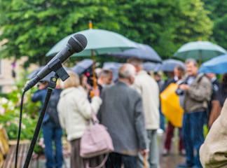 journalists working in rainy weather outdoors in park environment holding microphone and umbrella in live broadcasting.