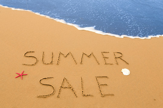 summer sale written in the sand on a sunny beach