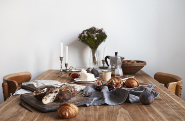 Perfect tasty provence breakfast on wooden table in white kitchen interior, empty white wall, daylight