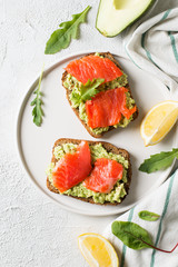 Toasts with avocado and salmon on plate