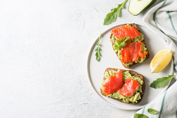 Toasts with avocado and salmon on plate