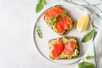 Toasts with avocado and salmon on plate
