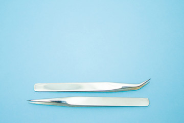 tools for Eyelash Extension Procedure. Two tweezers on blue background. copyspace mockup - Beauty and fashion concept