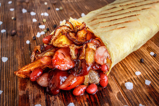 A traditional dish swirled in pita bread with ingredients from beans slices of potatoes and sausages.