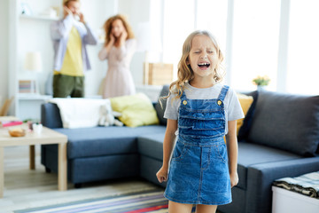 Little girl in casualwear crying and shouting while her parents shutting their ears on background