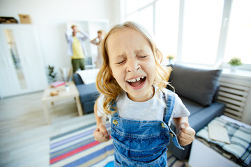 Little daughter shouting loudly while demanding something from her parents at home