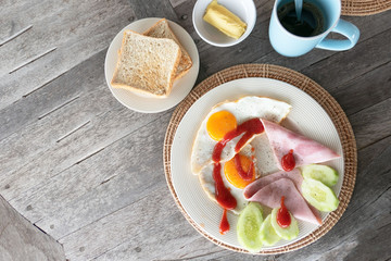 Fototapeta na wymiar Breakfast egg and ham on white plate and coffee on wooden table .