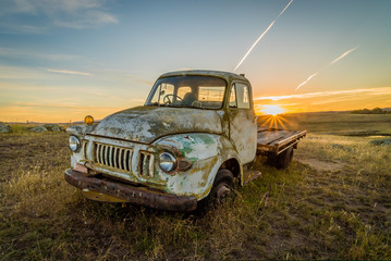 Old rusty car in a field in Australia with sunset in the background