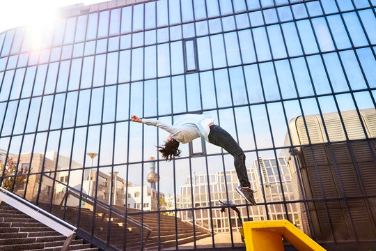 Frau macht Salto mit Spiegelung in Fenstern