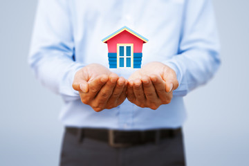 Real estate investment, property insurance and security concept. Protecting gesture of man and house model