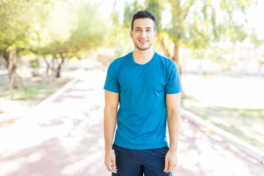 Male Athlete Smiling While Standing On Footpath In Park