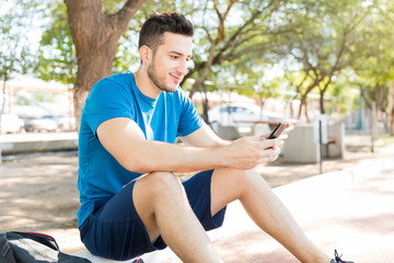 Fototapeta premium Sporty Man Text Messaging On Mobile Phone In Park
