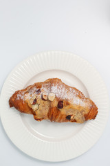 Freshly baked croissant with nuts on a white plate