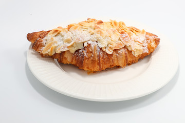 Freshly baked croissant with nuts on a white plate