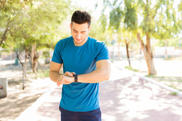 Man Checking Counts Of Steps On Smart Watch In Park