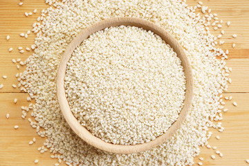 White sesame seeds on wooden background