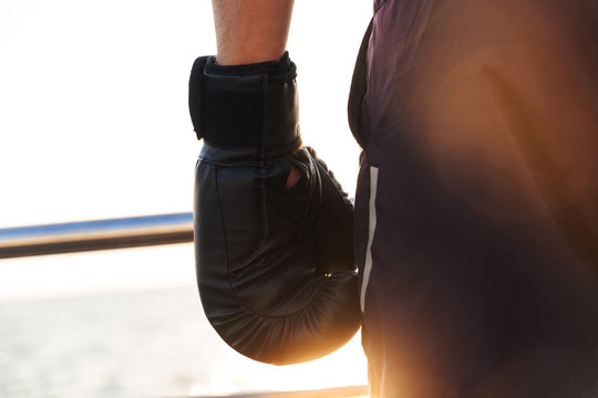 Cropped image of Sportsman in boxing gloves standing on beach