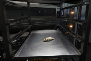 One frozen croissant on a baking tray in a bakery