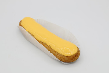 Fresh eclair with yellow icing on white background