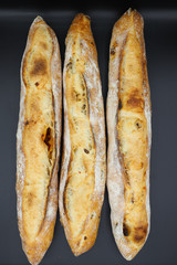 Three fresh French baguettes on dark background