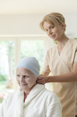 Smiling caregiver and sick elderly woman with cancer