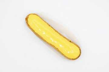Fresh eclair with yellow icing on white background