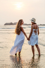 two sisters having fun at the sea at the sunset